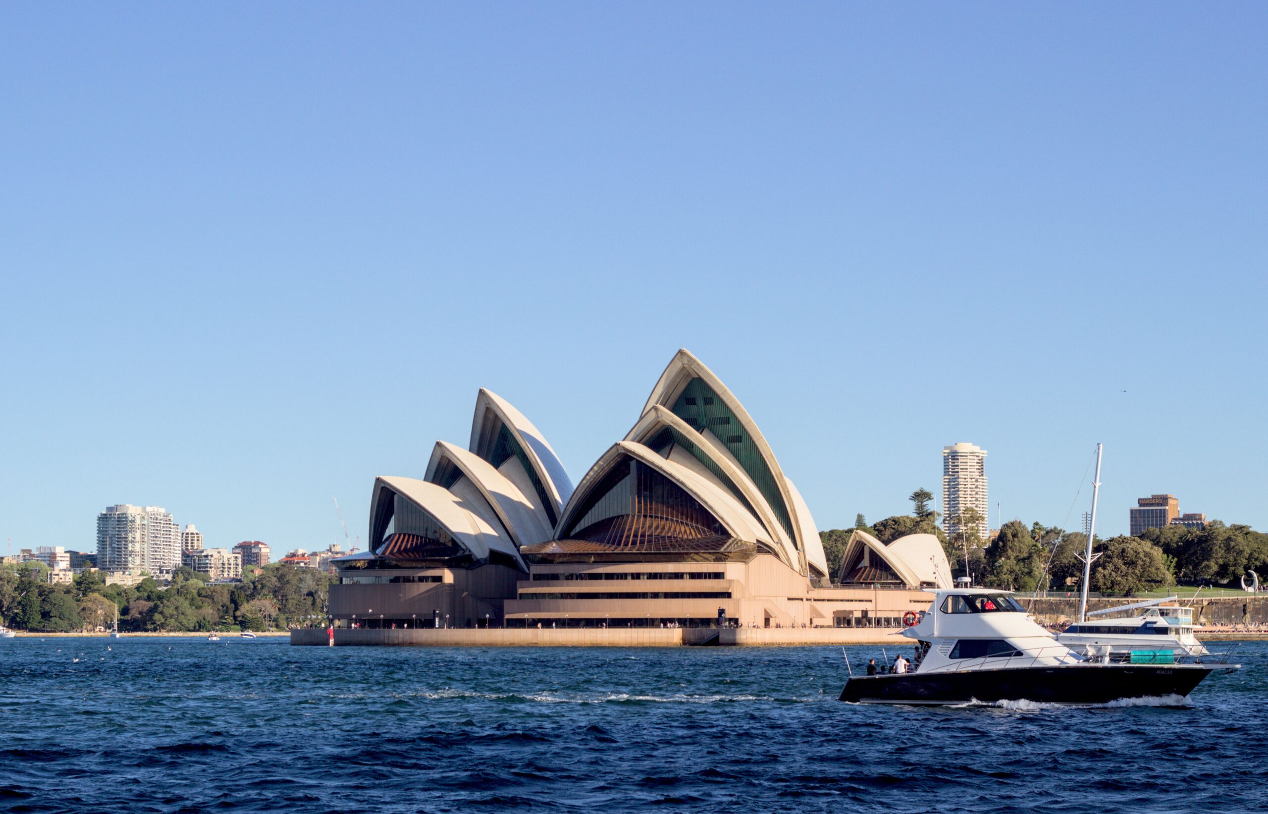 Iconic Sydney Opera House with boats in the foreground on a sunny day.